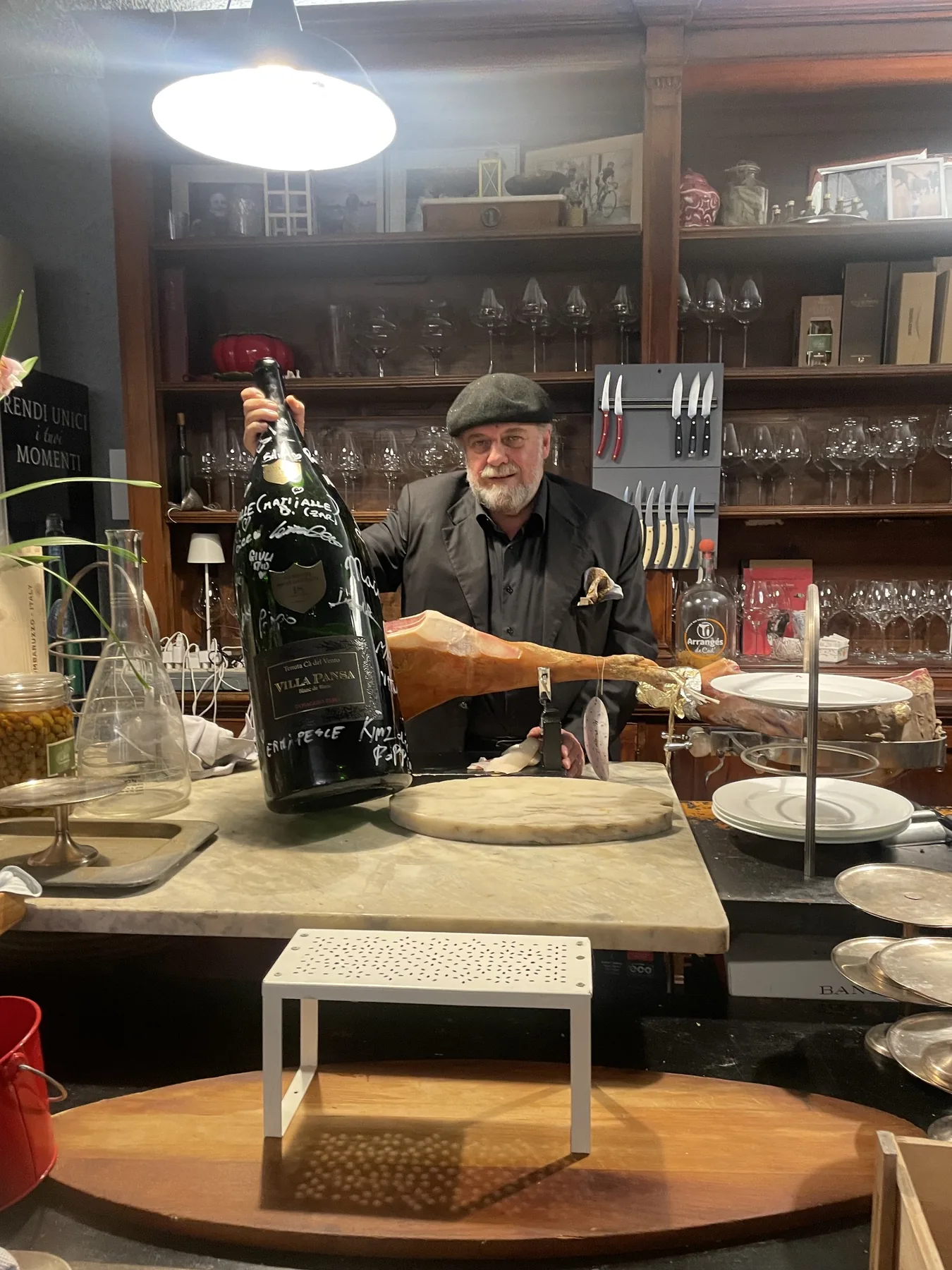 Al bancone del ristorante, con una bottiglia e un prosciutto